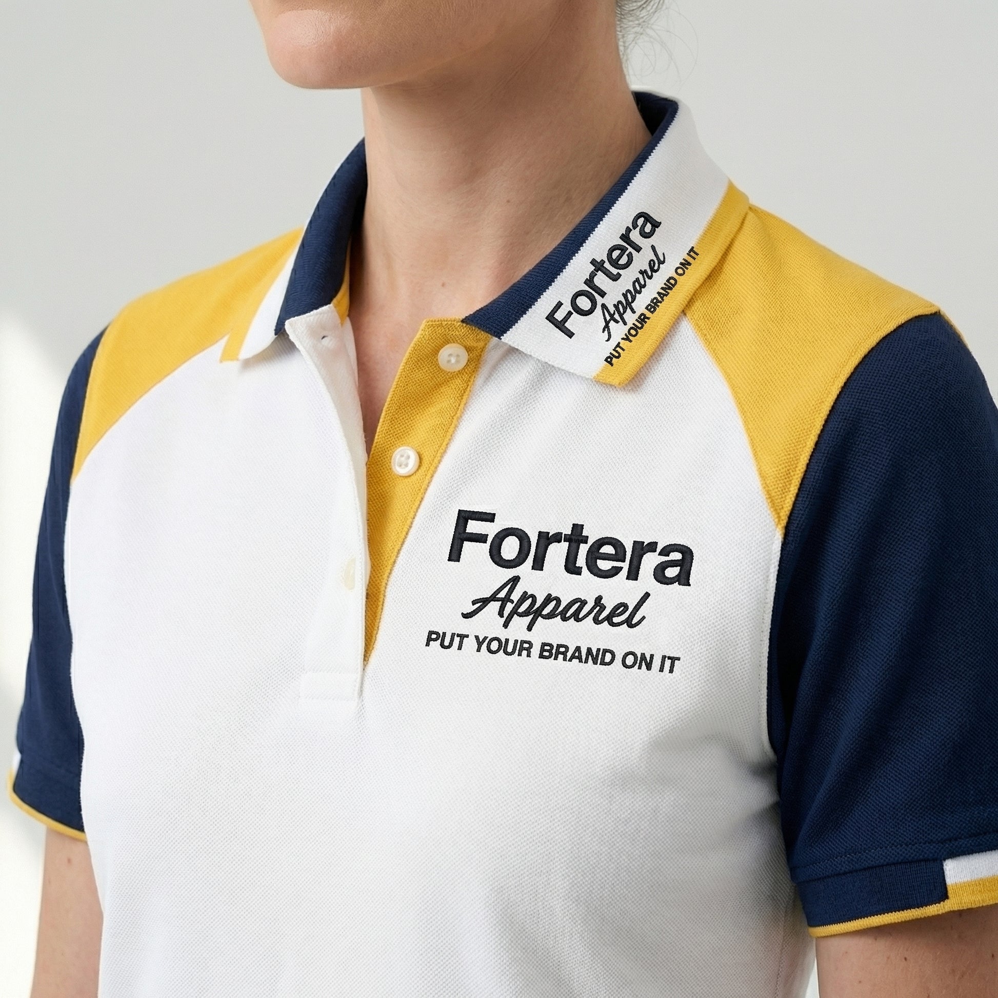 White bulk embroidered polo shirt with navy and yellow shoulder block - logo embroidery detail