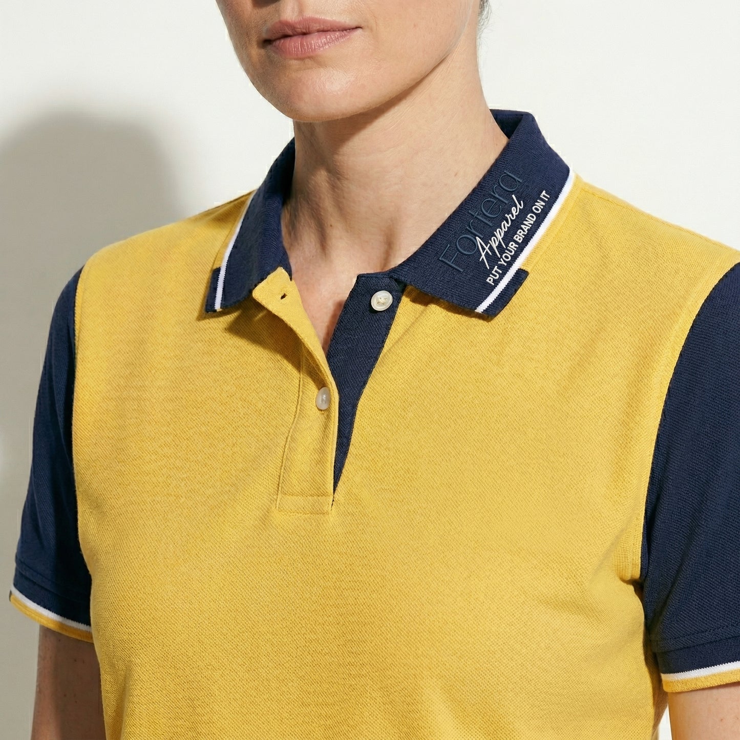 Yellow custom business polo shirt with navy shoulder panel and embroidered logo - logo embroidery detail