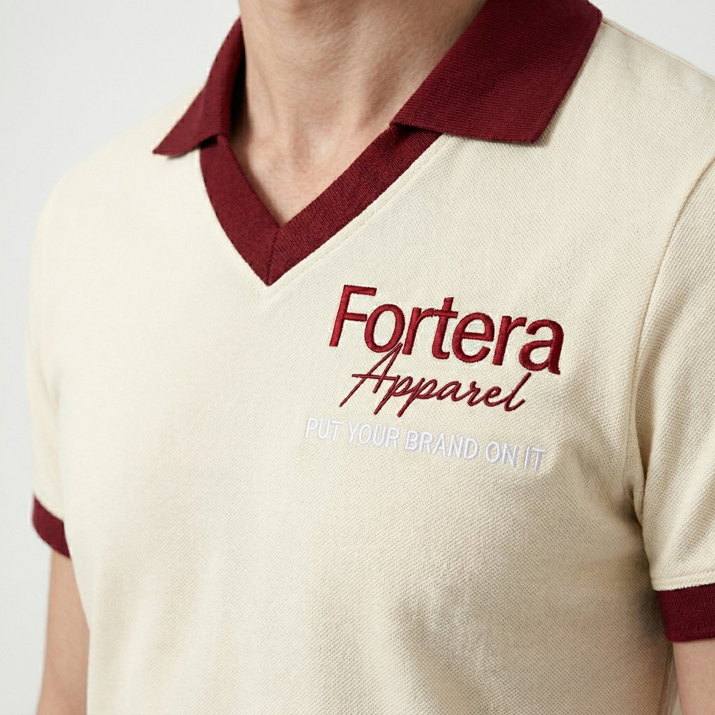 Cream custom staff polo shirt with burgundy heart collar V-neck accent - male fit