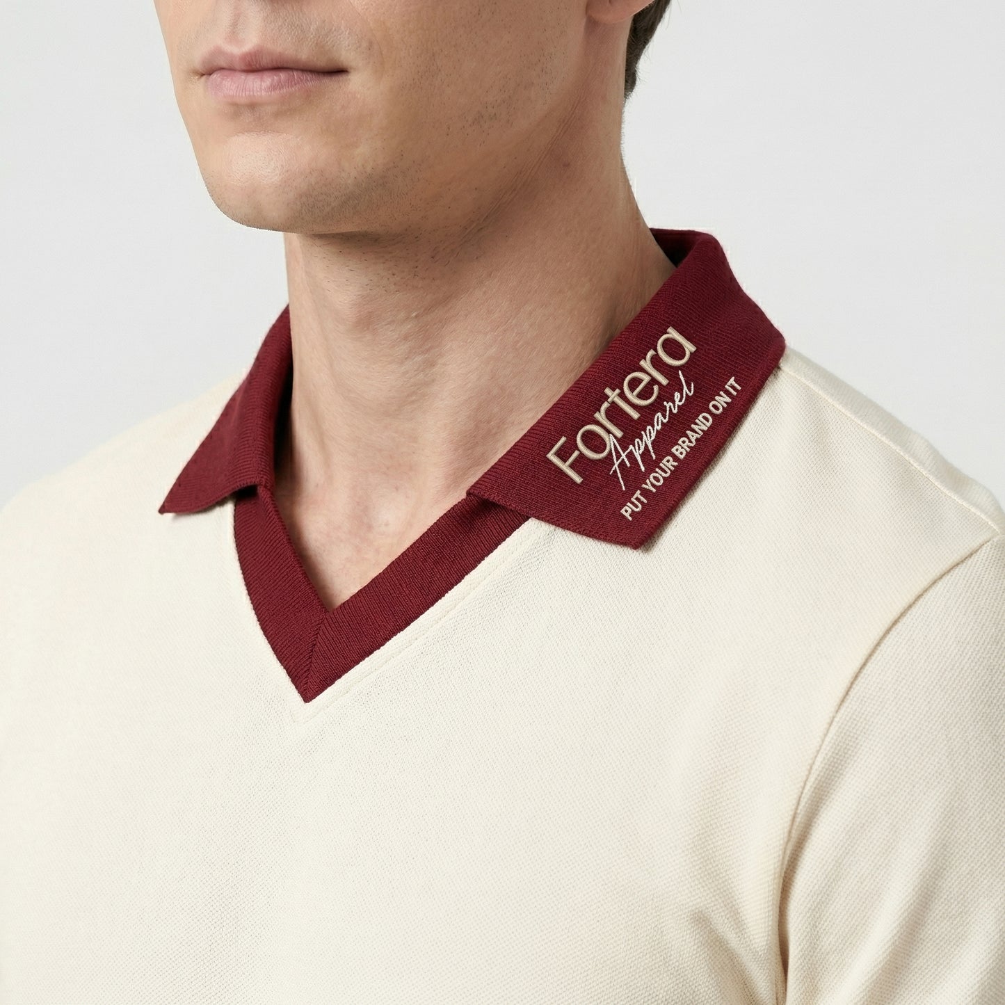 Cream custom staff polo shirt with burgundy heart collar V-neck accent - logo embroidery detail