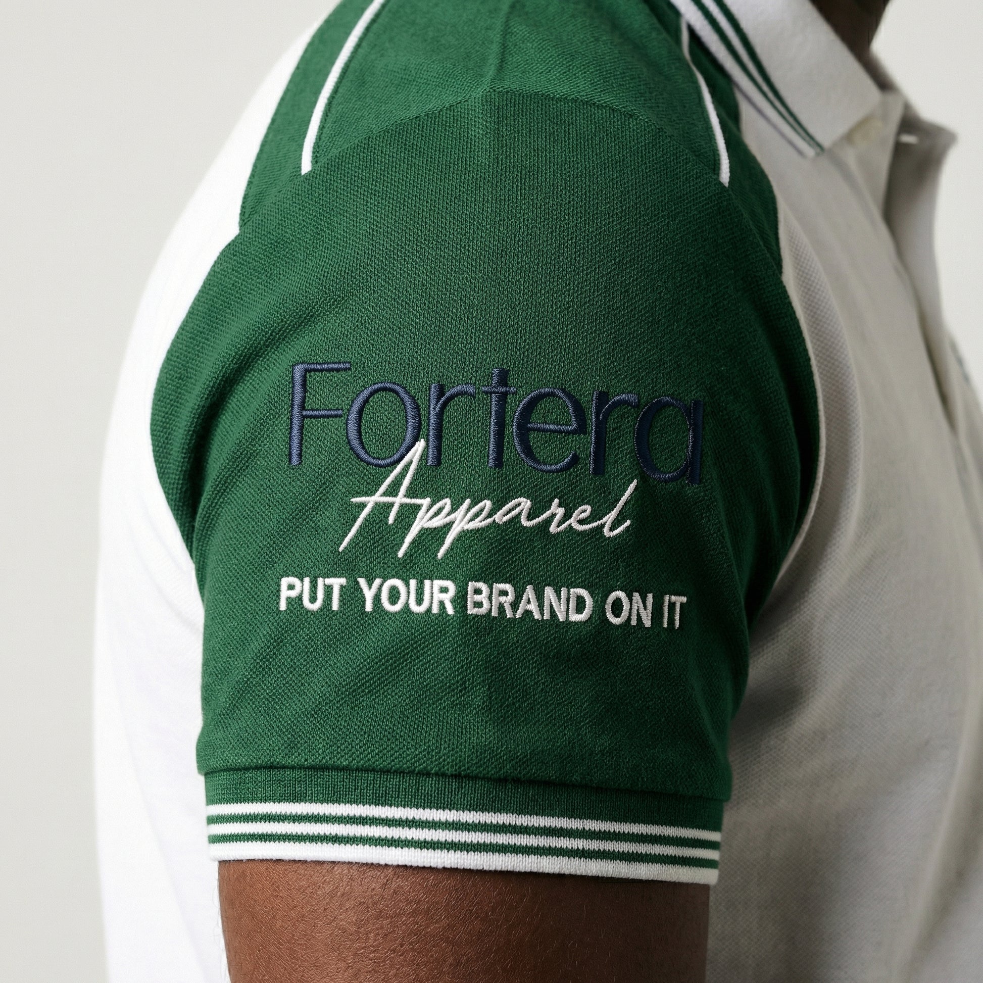 White moisture wicking polo uniform with forest green two-tone shoulder panel - logo embroidery detail